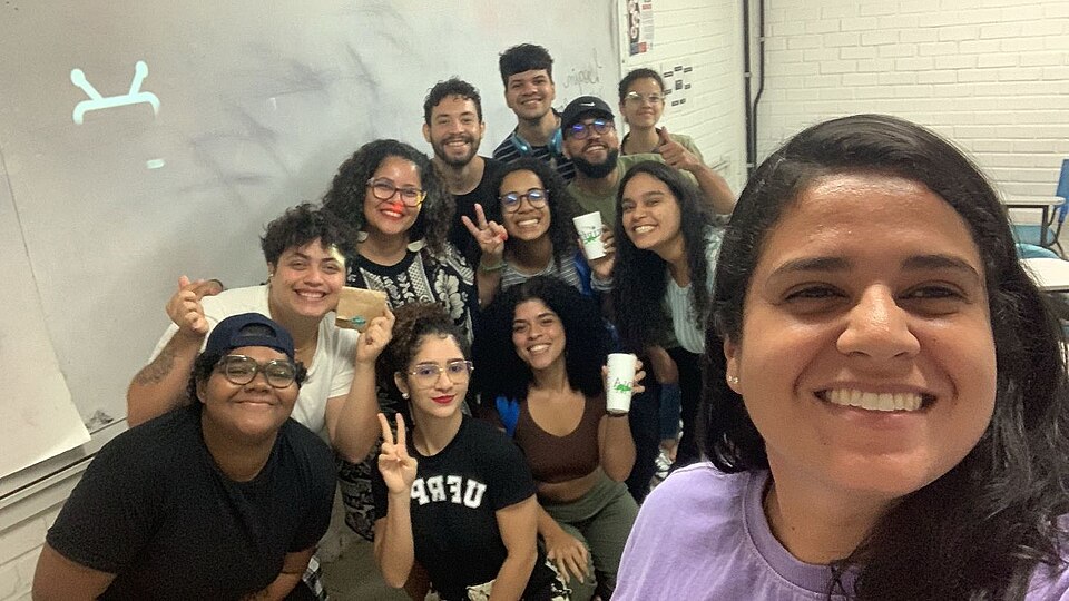 Estudantes e professora reunidos em sala de aula de universidade pública