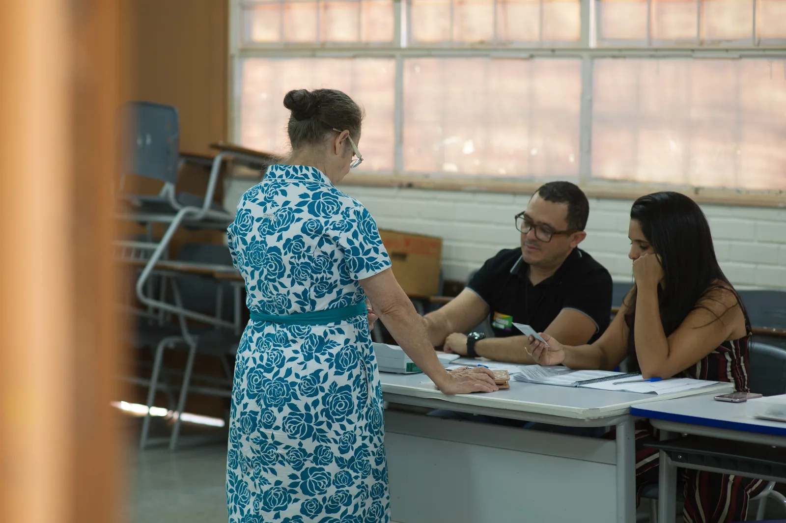 Eleitor vota em urna eletrônica acompanhado por mesários em seção eleitoral, Brasília, 28 de outubro de 2018.
