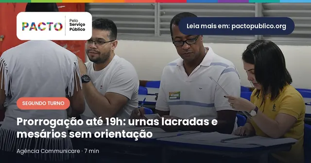 Mesários sentados atrás de uma mesa atendem uma eleitora em seção eleitoral instalada em escola